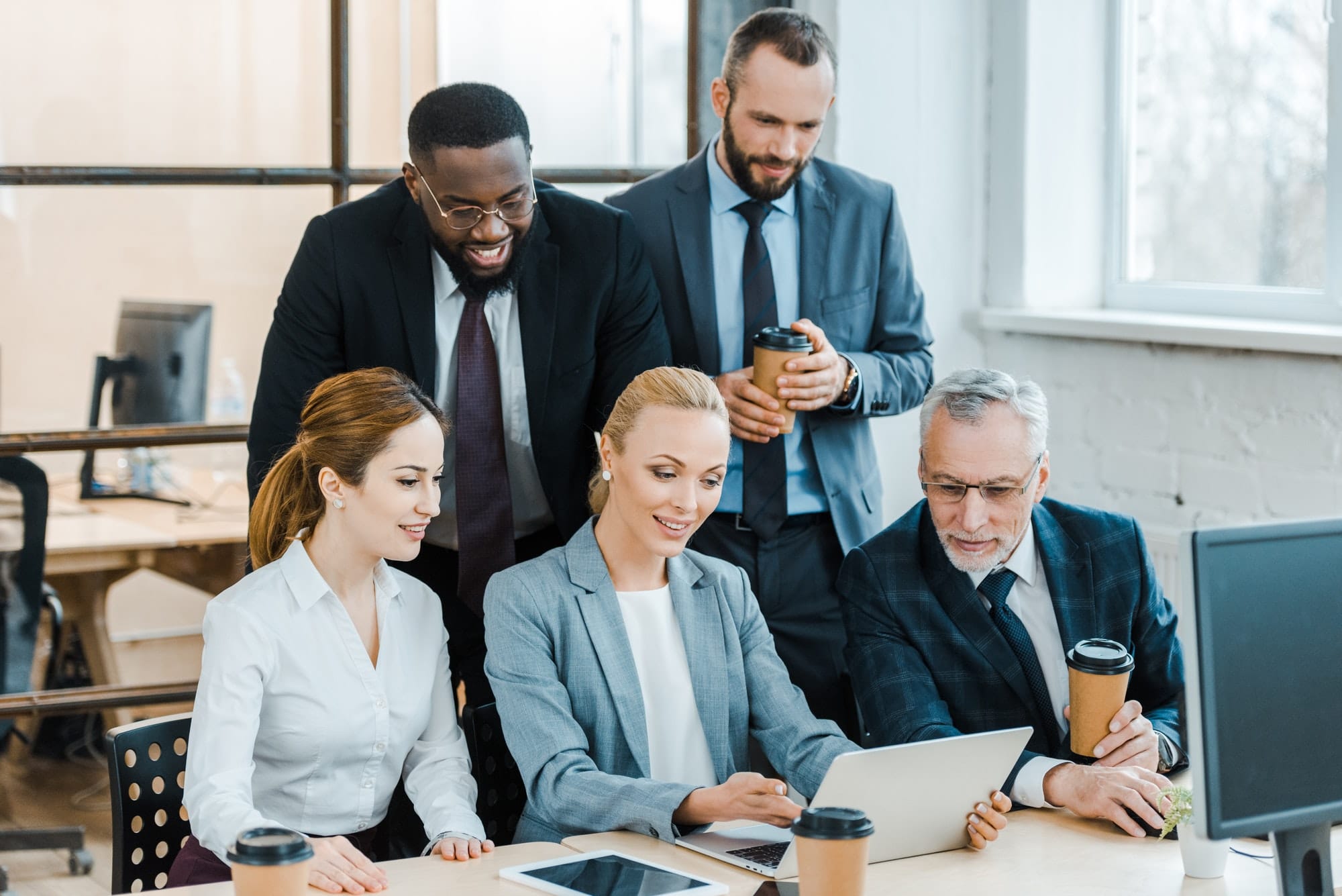 cheerful multicultural businessmen and businesswomen looking at laptop