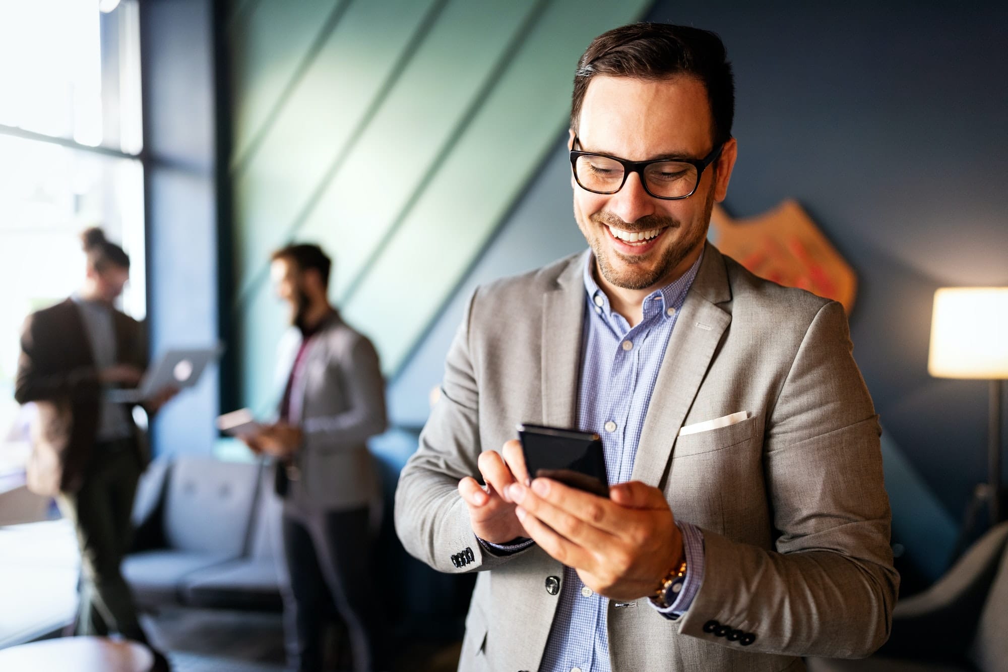 Handsome businessman checking emails on the phone in modern office